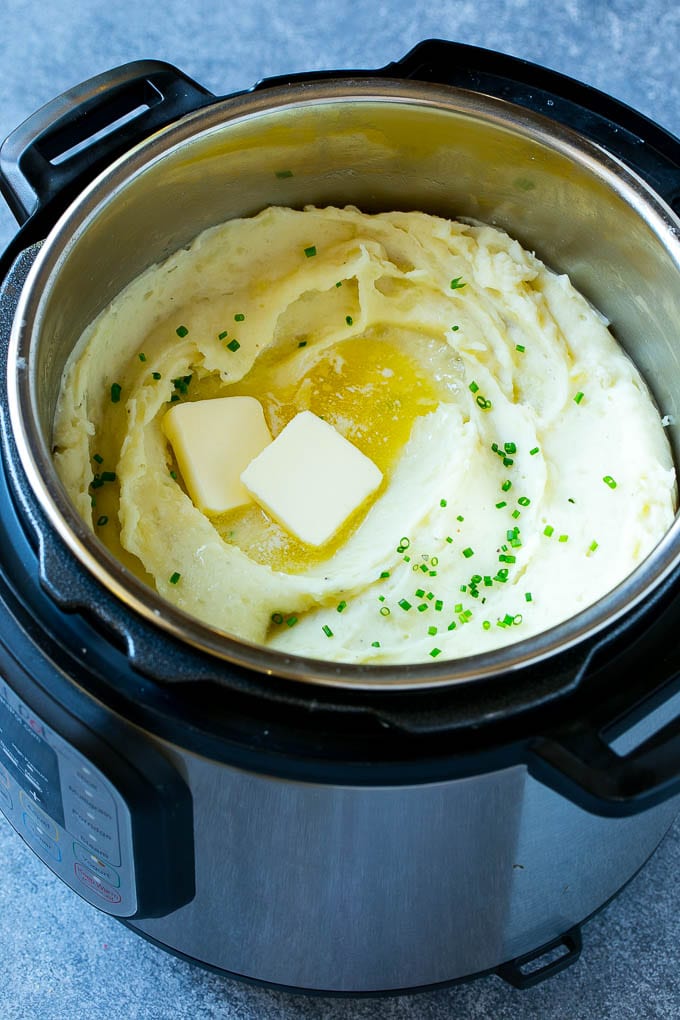 Instant Pot Mashed Potatoes Recipe | Pressure Cooker Mashed Potatoes | Easy Mashed Potatoes #potatoes #sidedish #instantpot #thanksgiving #dinner #dinneratthezoo Instant Pot mashed potatoes with butter and chives inside a pressure cooker.