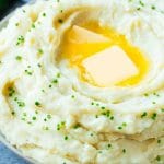 A bowl of fluffy Instant Pot mashed potatoes topped with pats of butter and sliced chives.