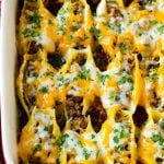 A baking dish of Mexican stuffed shells filled with ground beef and cheese.