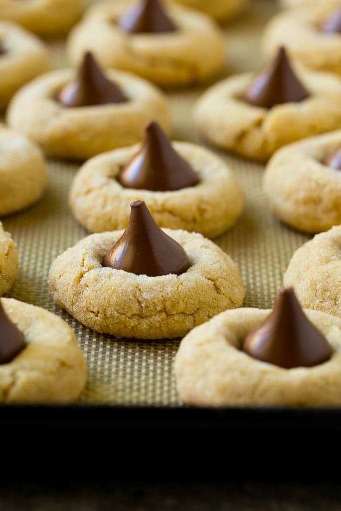 Baked peanut butter blossom cookies on a sheet pan.