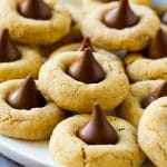 A plate with peanut butter blossoms stacked onto it.