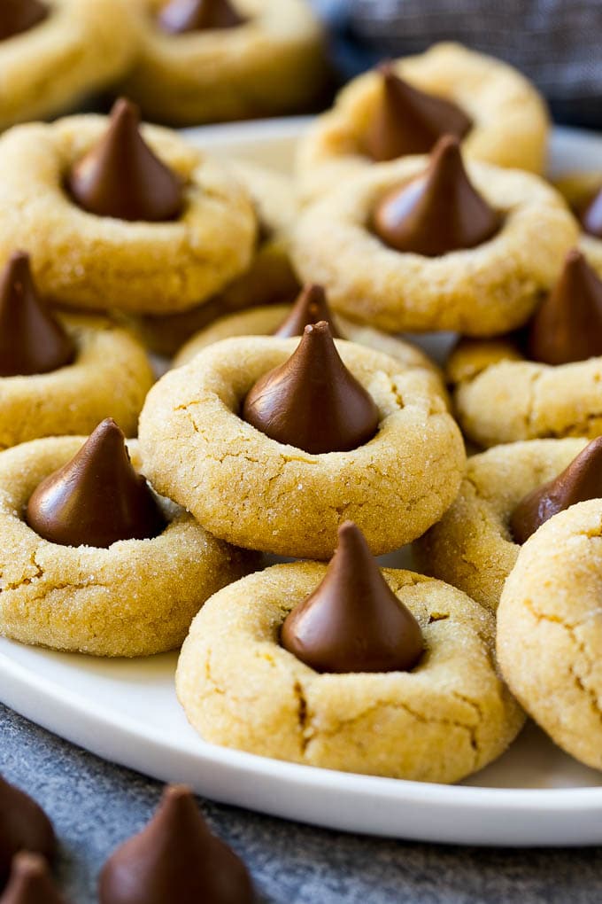 A plate with peanut butter blossoms stacked onto it.
