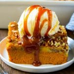 A slice of pumpkin dump cake topped with ice cream and caramel sauce.