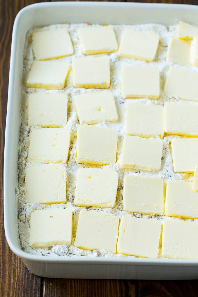 Cakemix gelaagd met in plakjes gesneden boter in een ovenschaal.