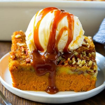 A slice of pumpkin dump cake topped with ice cream and caramel sauce.