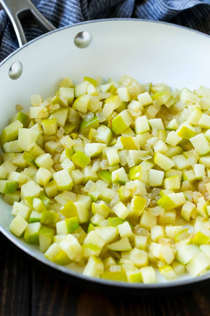 Sauteed onions and apples in a skillet.