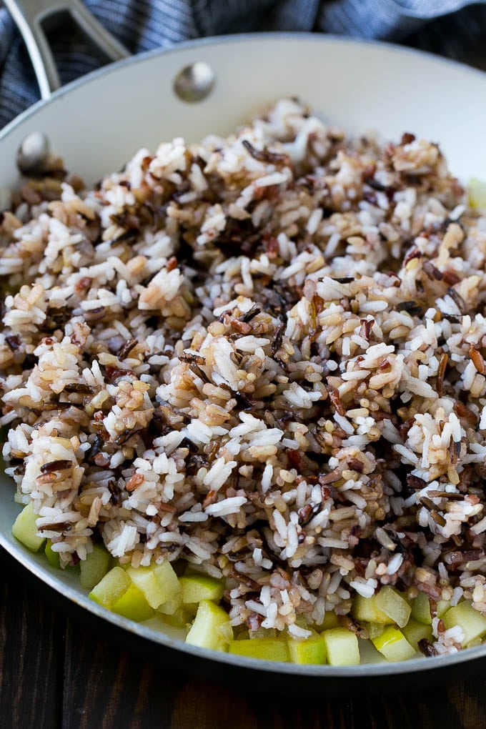 WIld rice, onions and apples in a skillet.