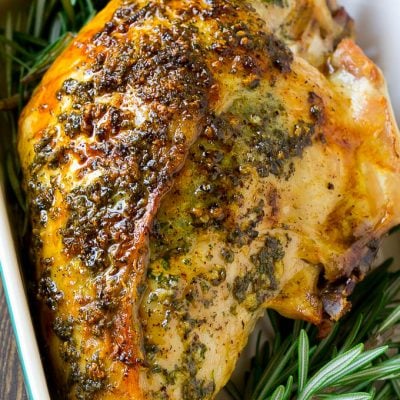 Garlic and herb roasted turkey breast in a baking dish with a rosemary garnish.