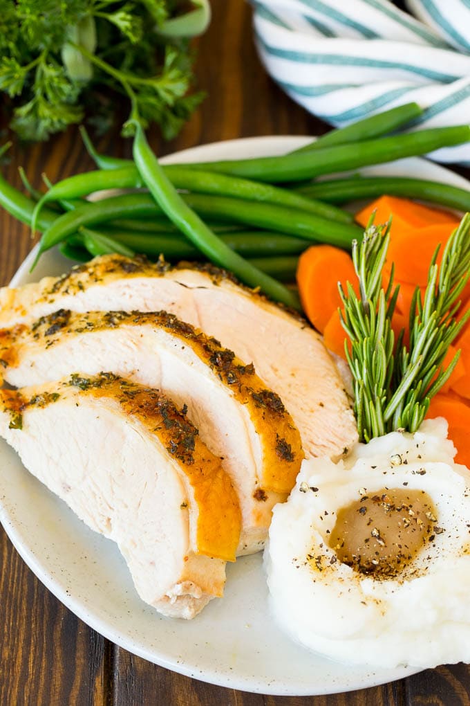 Sliced roasted turkey breast served with mashed potatoes and vegetables.