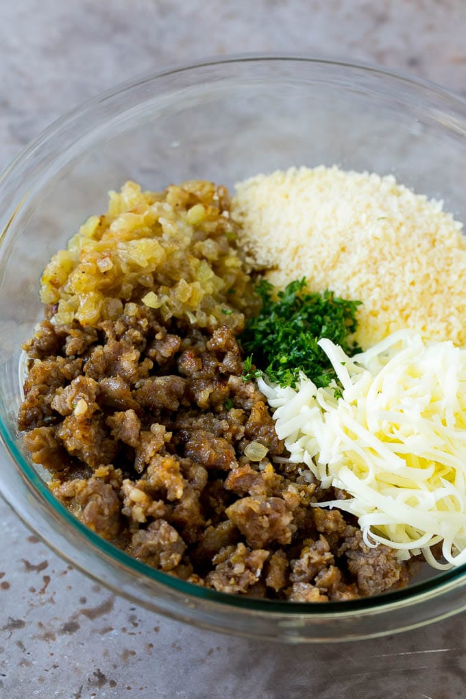 Crumbled Italian sausage, cheese, onions and herbs in a bowl.