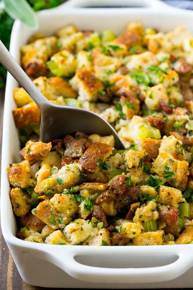 A baking dish of sausage stuffing with a serving spoon in it.