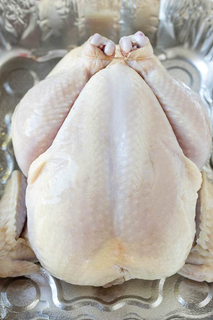 A raw chicken in a roasting pan.