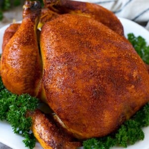 Smoked chicken on a serving platter garnished with parsley.