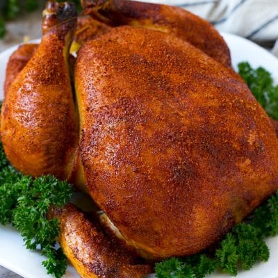 Smoked chicken on a serving platter garnished with parsley.