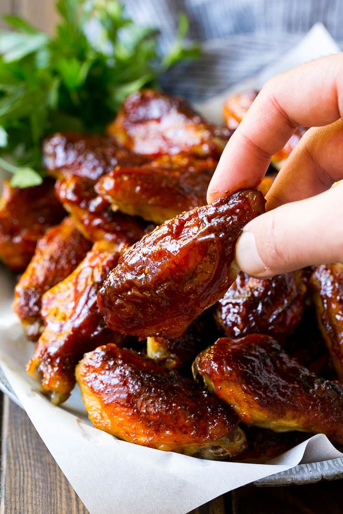 A pile of smoked chicken wings with a hand reaching out for one.