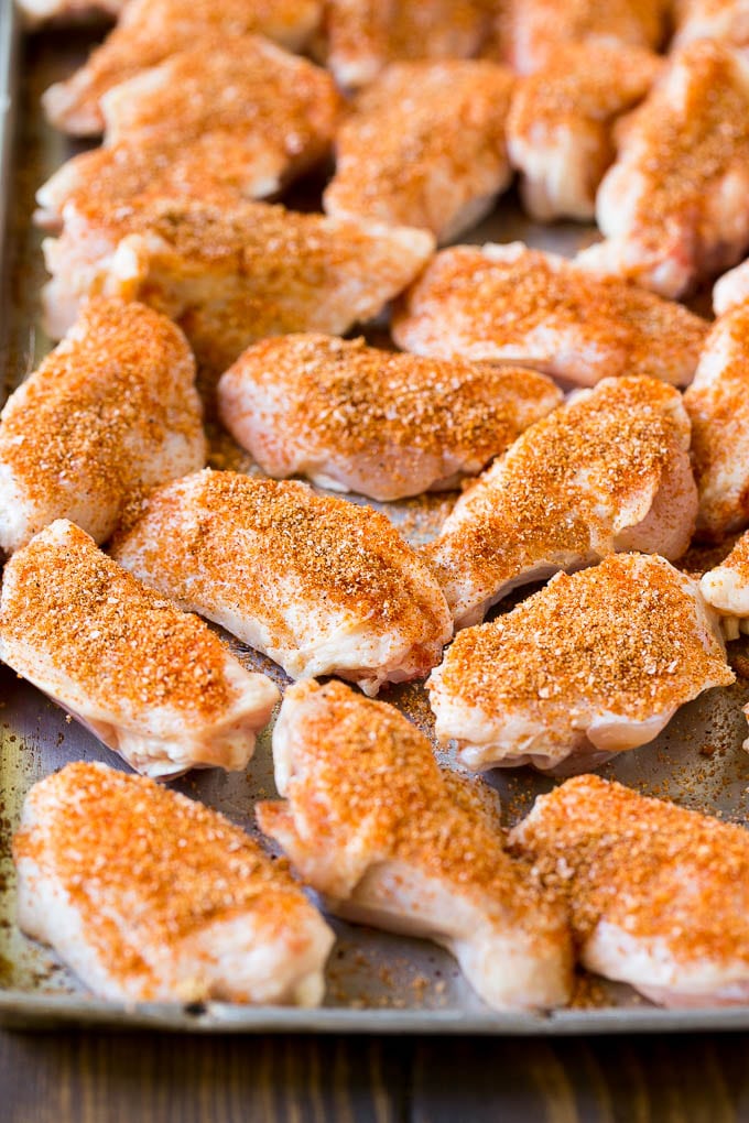 Raw chicken wings coated in homemade spice rub on a sheet pan.