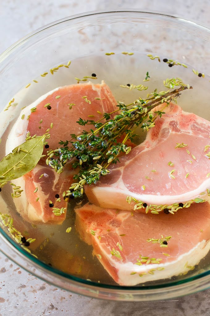 Pork chops in a bowl of brine.