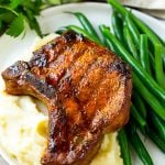 Smoked pork chops over mashed potatoes with green beans on the side.