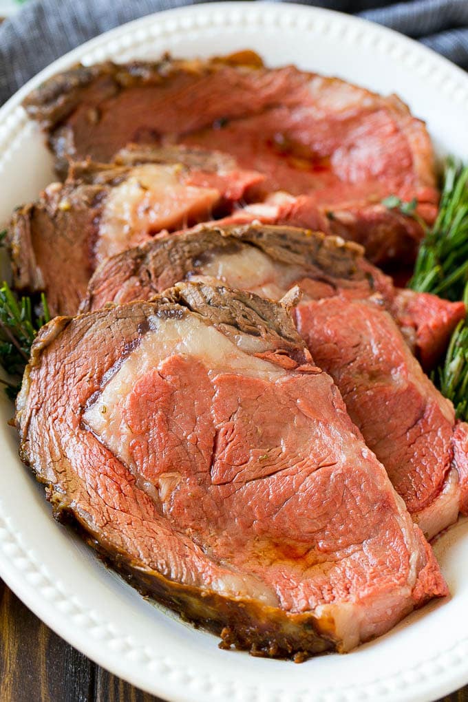 Slices of smoked prime rib garnished with fresh herbs.