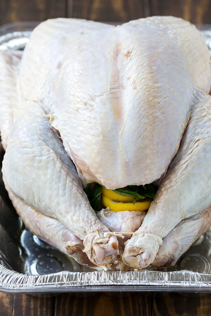 A raw turkey with the cavity stuffed with onion, lemon and herbs.
