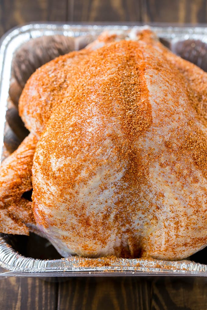 An uncooked turkey coated in spice rub.