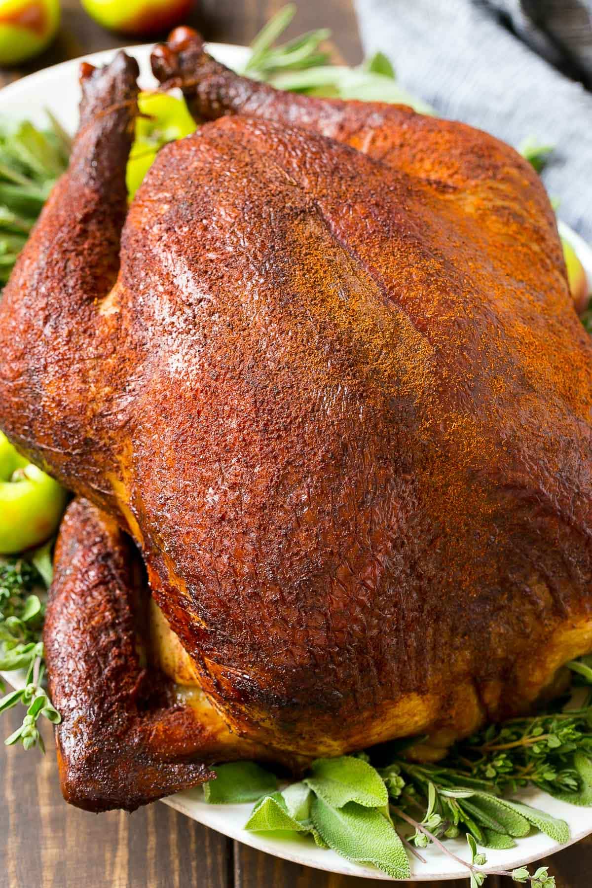 A whole smoked turkey garnished with herbs.