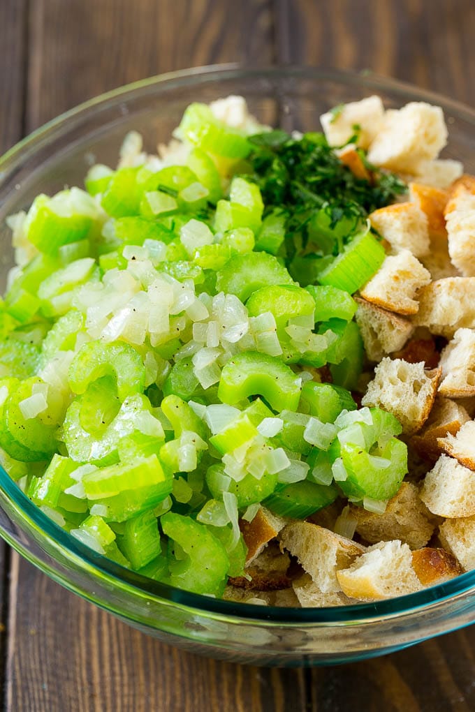 Bread cubes, celery, onion and herbs in a mixing bowl.