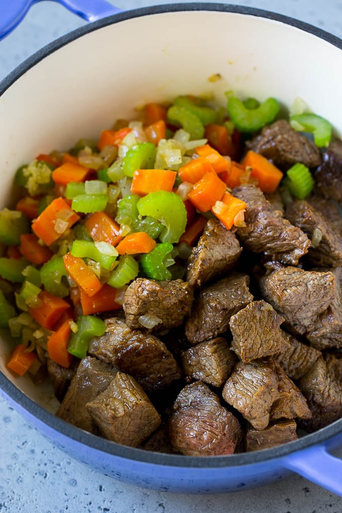 Beef stew meat, carrots, onion and celery in a pot.