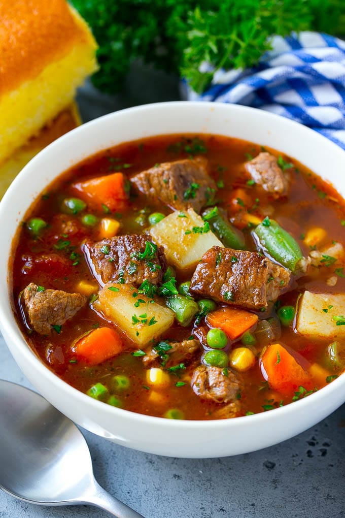 A bowl of vegetable pink meat soup with carrots, celery, onions, potatoes, tomatoes, corn and peas.  Vegetable Red meat Soup vegetable beef soup 5
