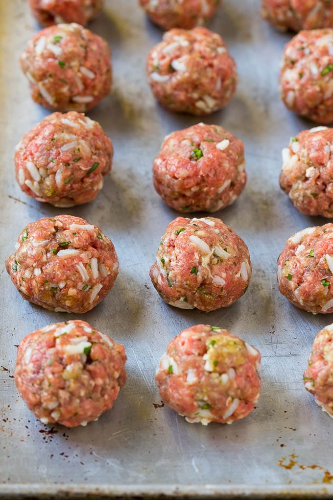 Uncooked beef and rice meatballs on a sheet pan.