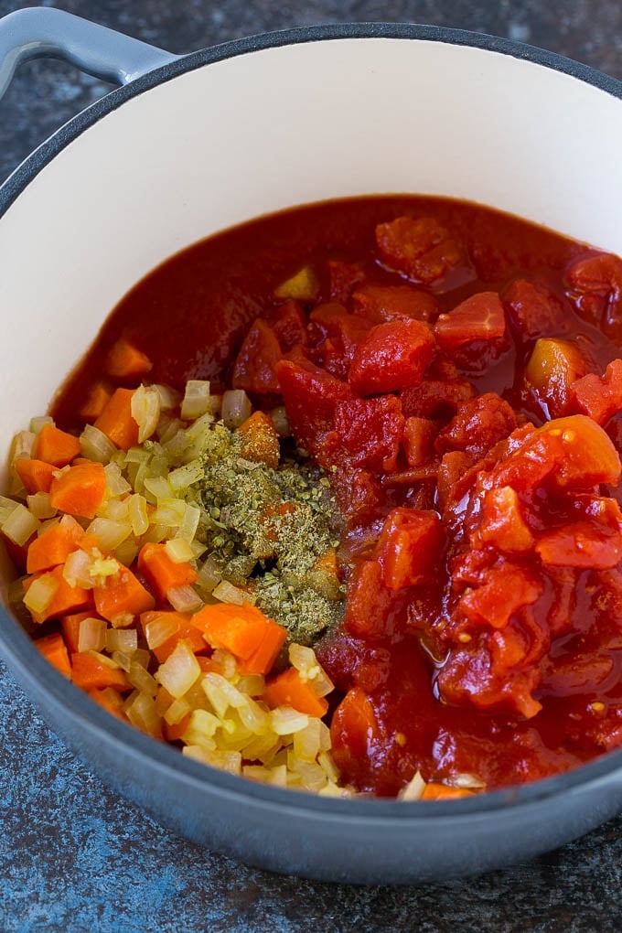 Vegetables, tomatoes and herbs in a soup pot.