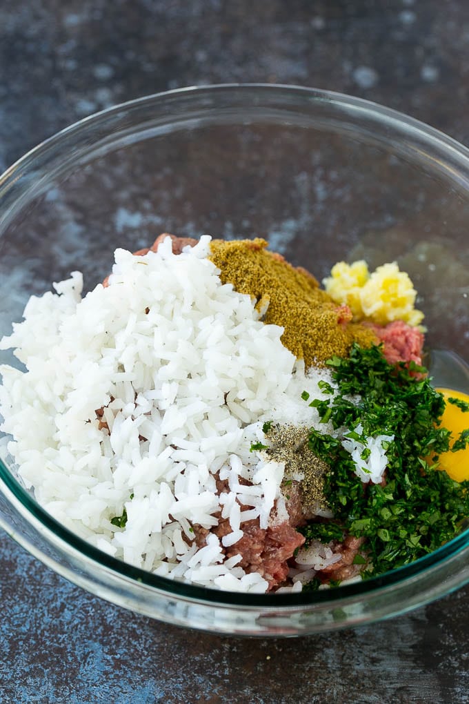 Ground beef, rice, herbs and garlic in a mixing bowl.