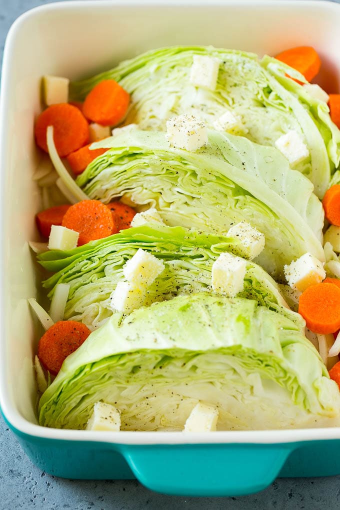 Cabbage, carrots, onions, pieces of butter and seasonings in a baking dish.