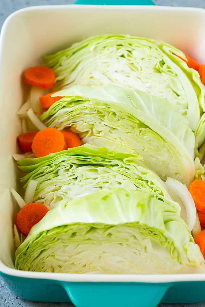 Wedges of cabbage, sliced carrots and onion in a baking dish.