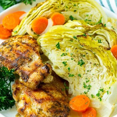 A plate of grilled chicken along with braised cabbage, carrots and onions.
