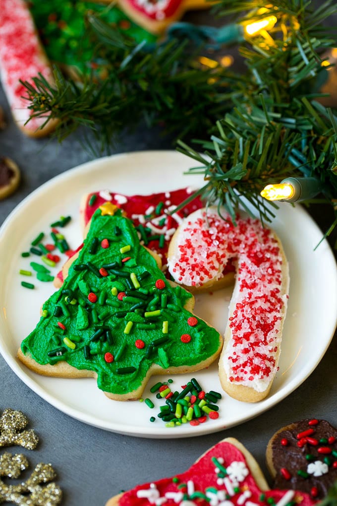 A selection of Christmas sugar cookies served on a plate, with holiday decorations in the background.