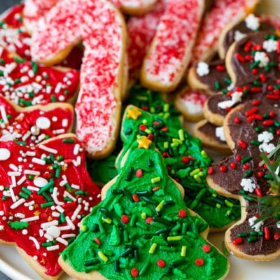 A serving plate of Christmas sugar cookies decorated with frosting and sprinkles.