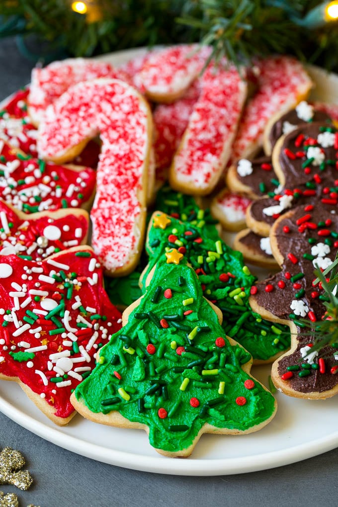 A serving plate of Christmas sugar cookies decorated with frosting and sprinkles.
