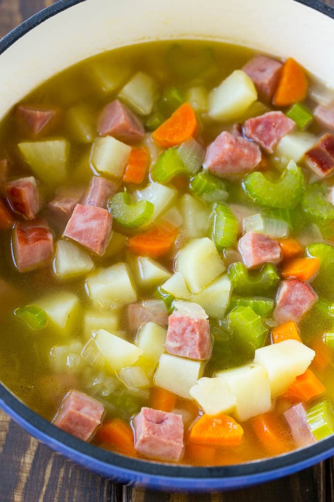 A pot full of ham, potatoes and vegetable simmered in chicken broth.