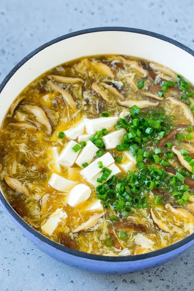 Hot and sour soup with diced tofu and green onions in it.