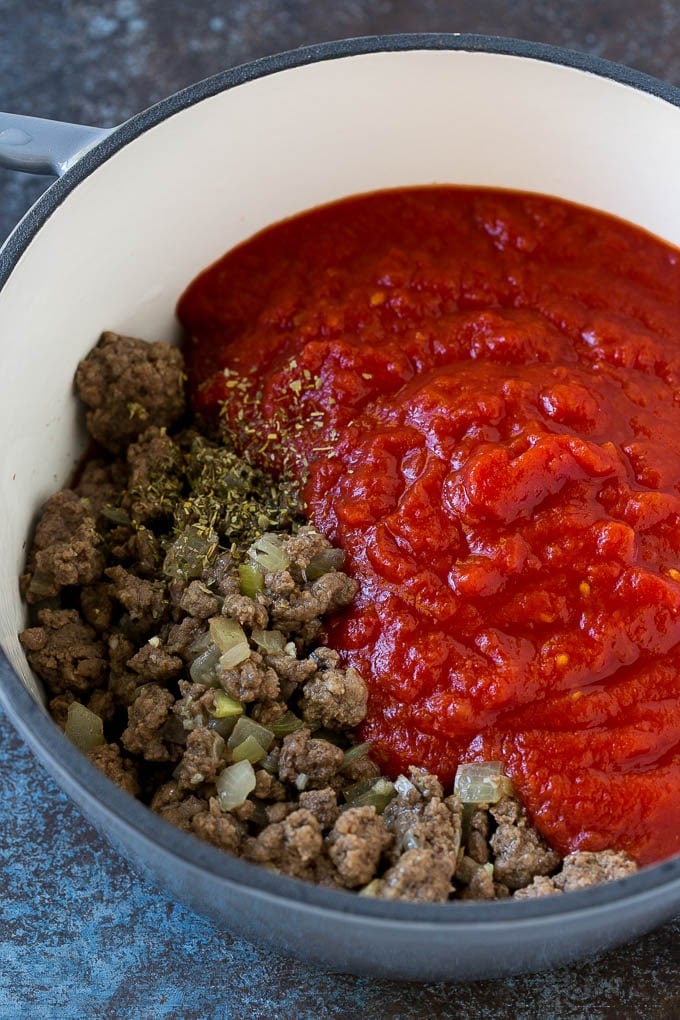 Cooked ground beef, onions and crushed tomatoes in a soup pot.