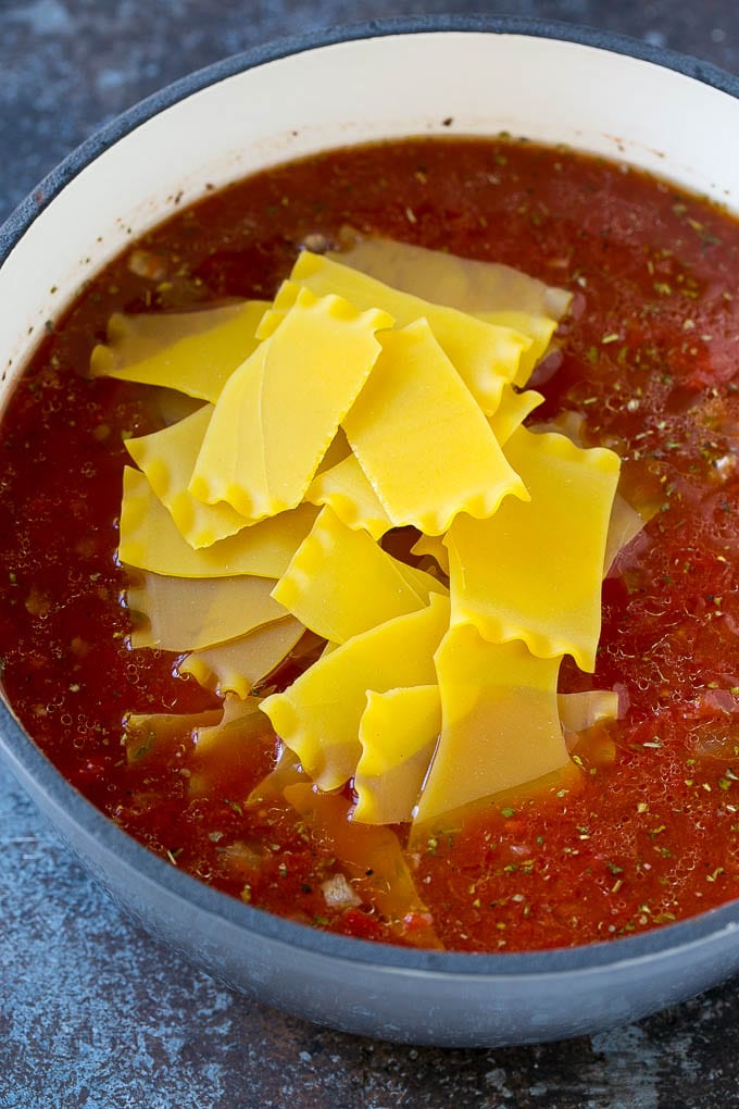 A pot of soup with broken lasagna noodles in it.