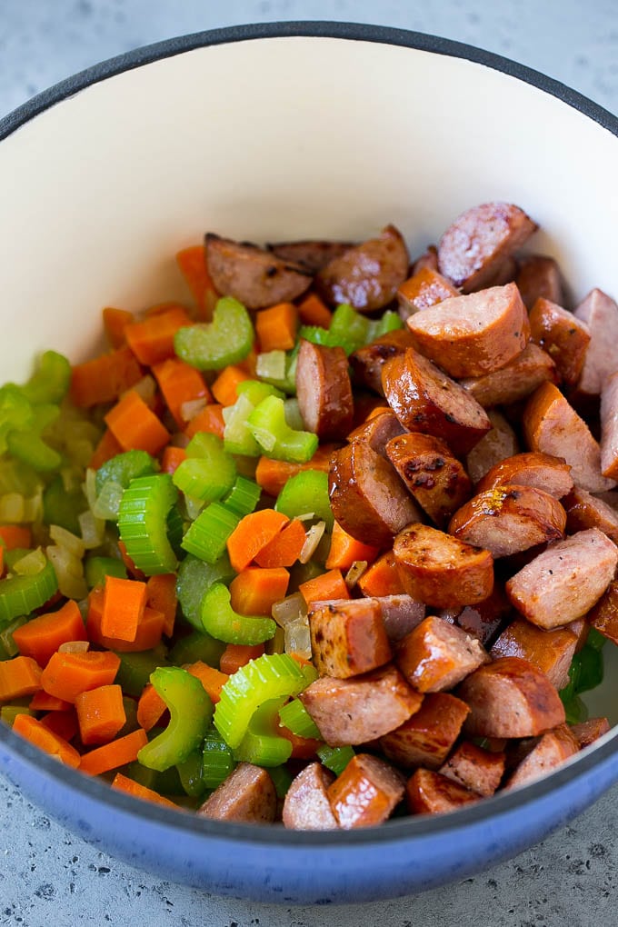 Sauteed vegetables and smoked sausage in a pot.