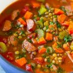 A pot of lentil soup made with carrots, celery, tomatoes and smoked sausage.