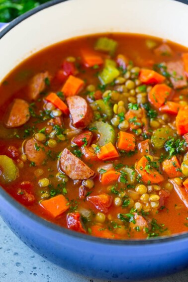 A pot of lentil soup made with carrots, celery, tomatoes and smoked sausage.