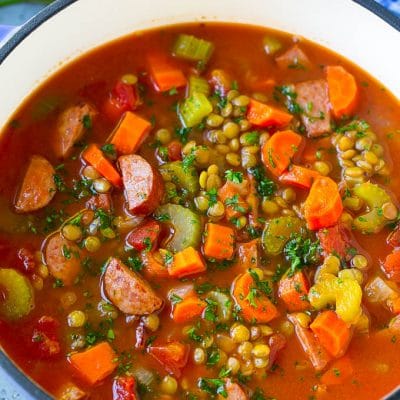 A pot of lentil soup flavored with vegetables, tomatoes and smoked sausage, then garnished with chopped parsley.
