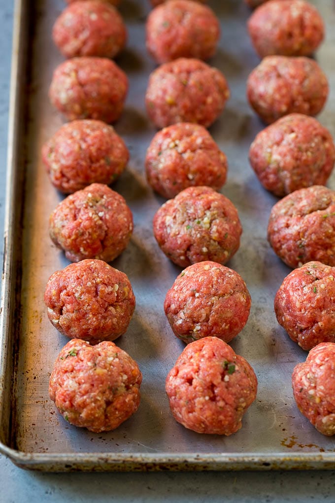 Raw meatballs on a sheet pan ready to go into the oven.