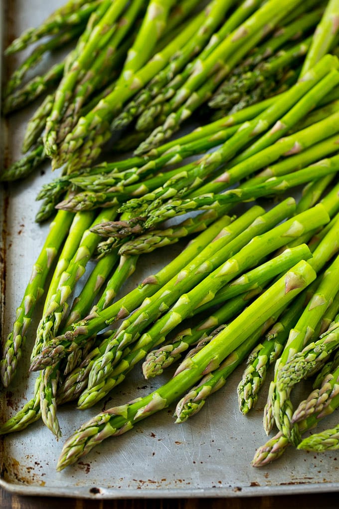 Raw asparagus spears on a sheet pan.