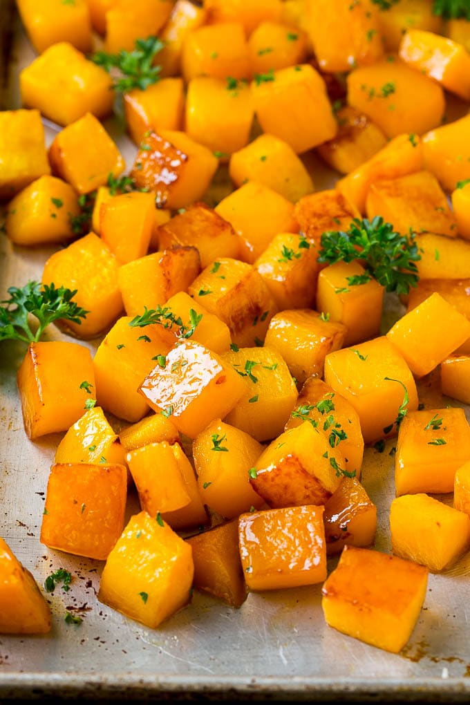 Roasted butternut squash with brown sugar and maple syrup, garnished with chopped parsley.