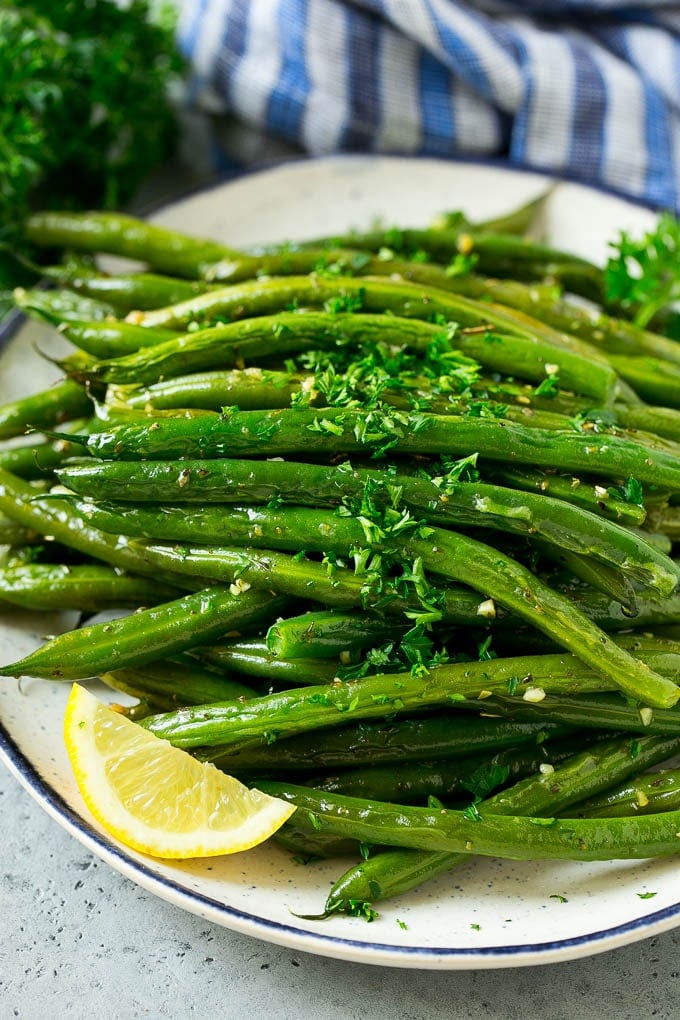 Roasted green beans on a serving plate topped with chopped parsley.
